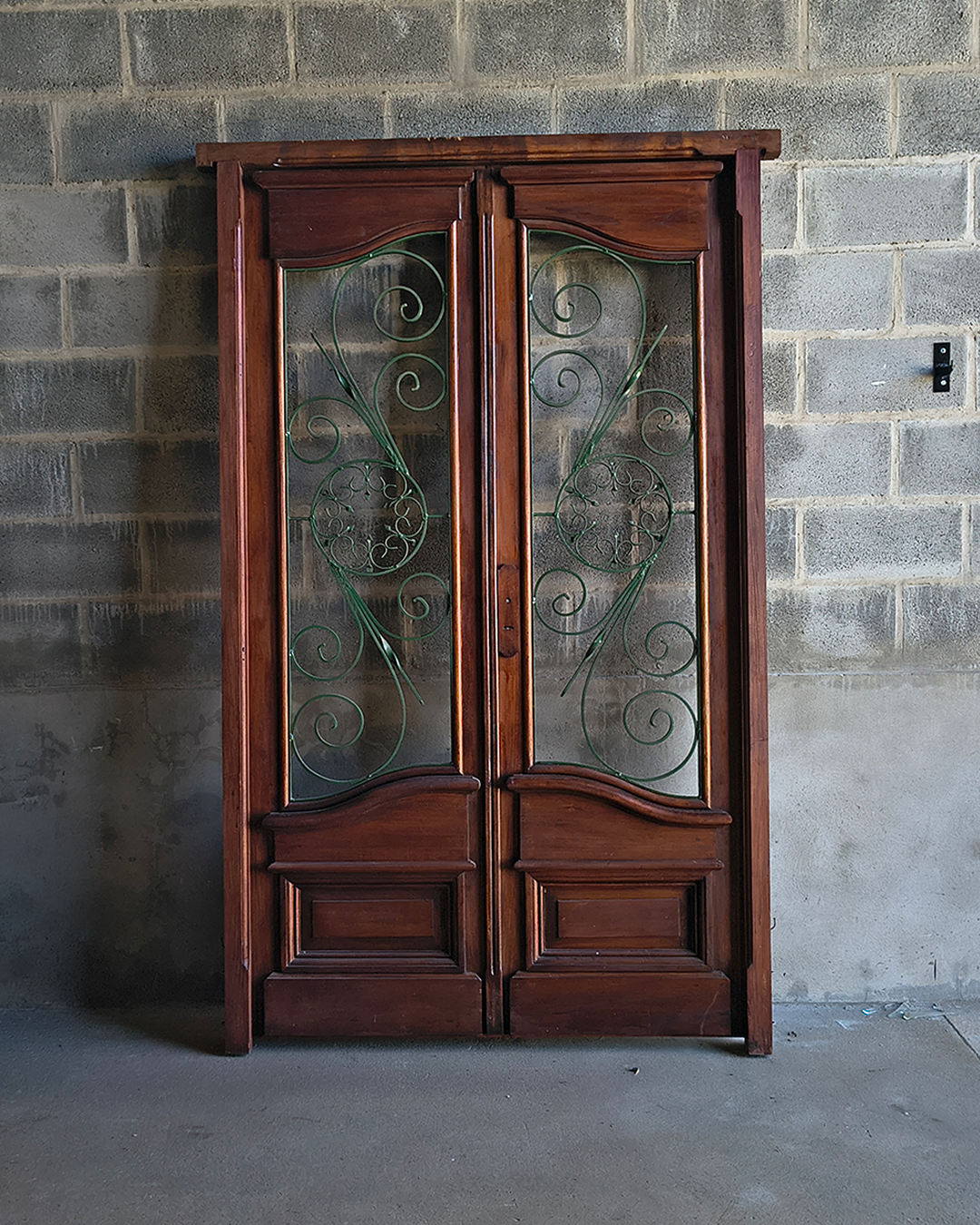 Puerta doble de madera maciza con detalles de hierro artesanal y diseño clásico.
